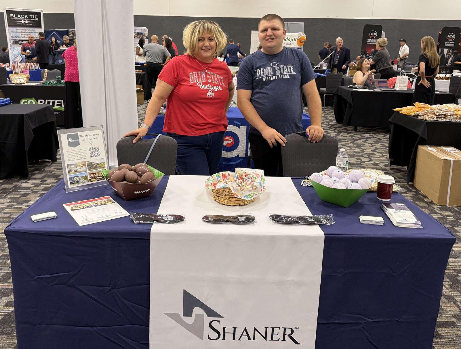 two people standing behind a table at a trade show