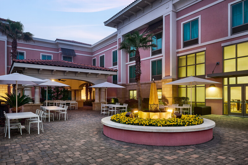 a building with a fountain and tables and umbrellas