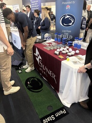 a group of people standing around a table with golf balls and water bottles